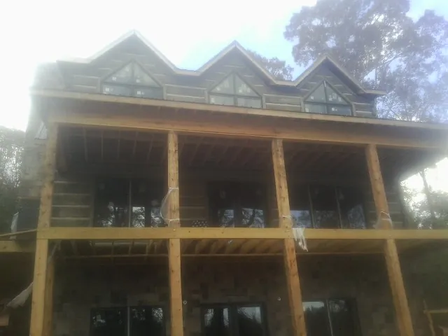 Dormers and porch framing on a large log home under construction — Roof Coating work by our crew in Virginia