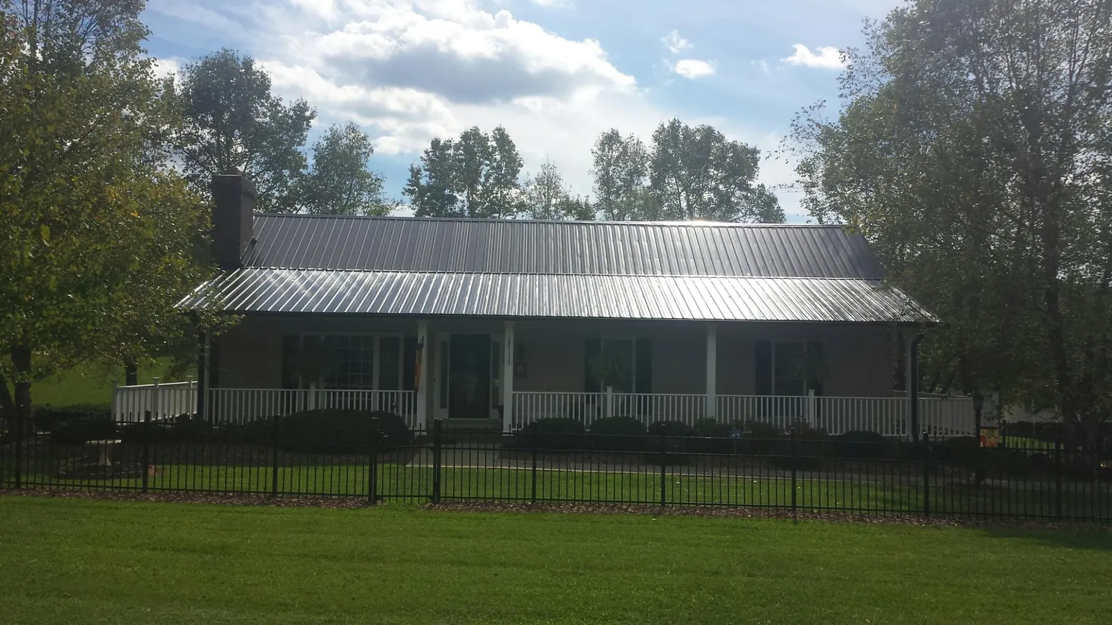 Gray metal roof on a brick ranch with a full width front porch — Gutter Guard Installation work by our crew in Virginia