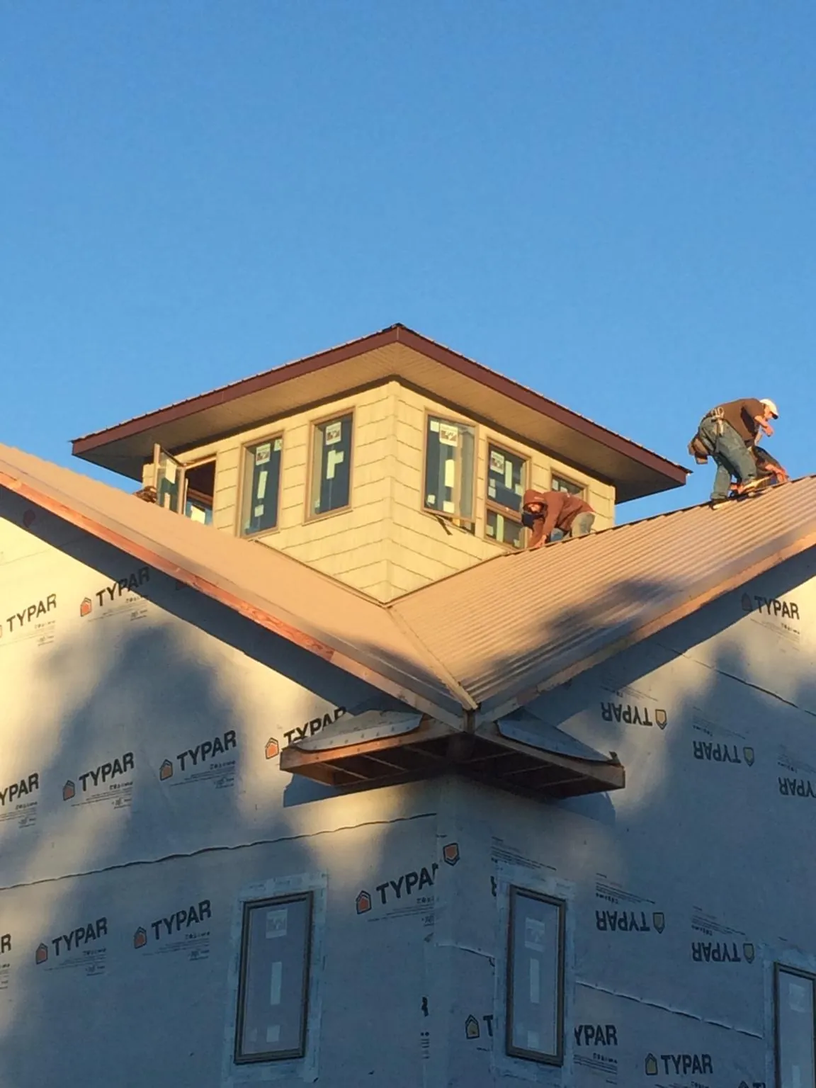 Roofers working around a rooftop cupola on a new metal roof at sunset — Roof Waterproofing in Virginia by Roofing Brothers